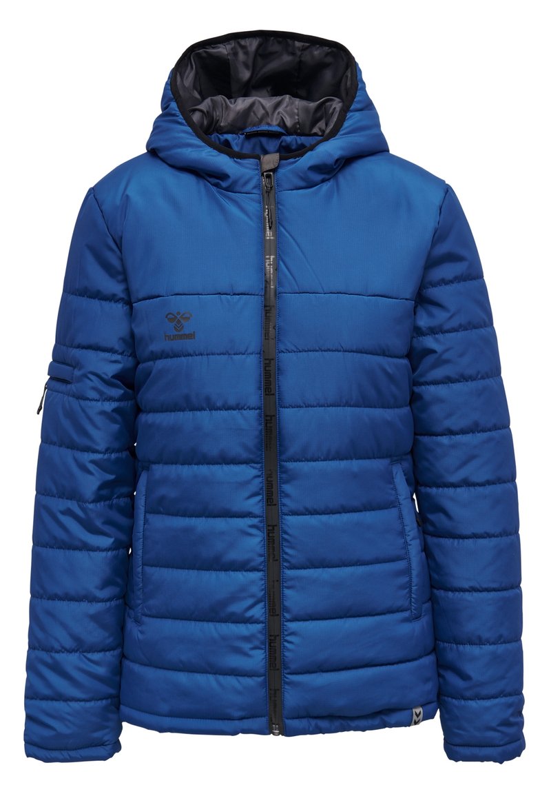 Giacca a vento blu con cappuccio, chiusura con zip e cuciture orizzontali. Presenta una fodera interna nera e un logo sul lato sinistro del petto.
