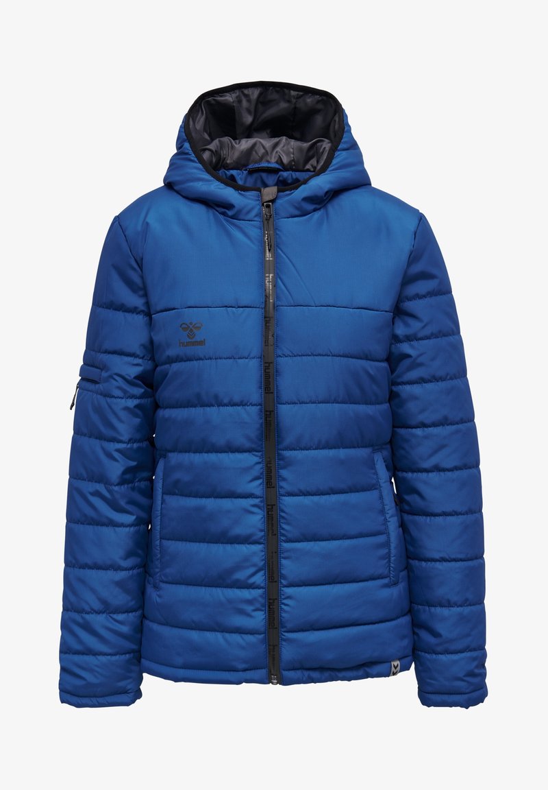 Giacca a vento blu con cappuccio, chiusura con zip e cuciture orizzontali. Presenta una fodera interna nera e un logo sul lato sinistro del petto.