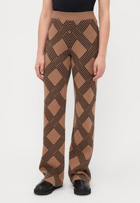 Bruine gestreepte broek met een groot zwart diamanten patroon, gebreide stof, wijd uitlopende pijpen, hoge taille en een zachte textuur.