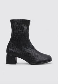 Botas de tobillo negras hechas de cuero texturizado, con punta cuadrada y un tacón grueso. Diseño simple sin adornos.