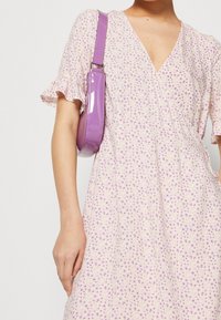 Floral-patterned dress in light pink with short ruffle sleeves, featuring a V-neckline. Paired with a purple patent leather shoulder bag.