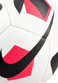 Pallone da calcio Nike con una superficie bianca testurizzata, disegni geometrici neri e rossi, e cuciture visibili.