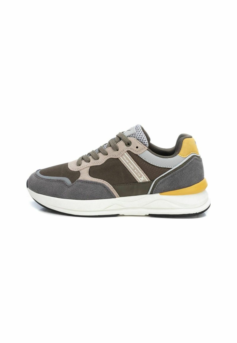 Chaussures de sport dans des tons de brun et de gris, avec des accents en mesh, un talon jaune et une semelle blanche à finition texturée.