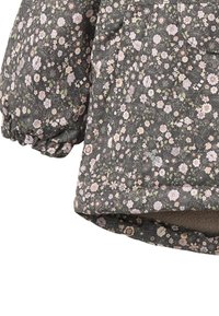 Tikkitakki, jossa tumma kukkakuvio, sisältäen vaaleanpunaisen ja vihreän sävyjä. Puhallushihat, joissa on kuminauhalla varustetut mansetit ja pehmeä vuori sisäpuolella.