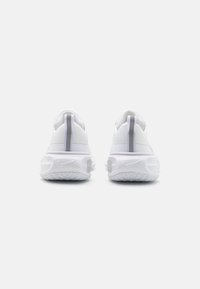 Scarpe sportive bianche con una tomaia testurizzata, collare imbottito e accenti grigi riflettenti; con suola spessa e ammortizzata e dettagli del logo.