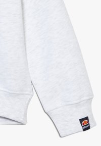 Witte, fleeceachtige sweatshirts met geribbelde manchetten en een klein logolabel op de mouw. De stof heeft een subtiele textuur.