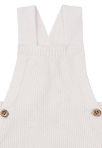 Witte gebreide overall met brede banden, voorzien van houten knopen aan elke zijde en een gestructureerd, ribbelpatroon.