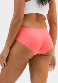 Slip hipster color corallo con una texture liscia. Design a vita alta con cuciture minime per il massimo comfort e una silhouette senza cuciture.
