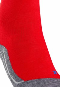 Rote Socke mit gerippter Textur, grauem Zehen- und Fersenbereich sowie einem blauen Logo near dem oberen Ende. Das Design ist nahtlos.