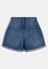 Riflové šortky ve středně modrém odstínu s ohrnutým lemem, mají dvě zadní kapsy a zelenou výšivku loga na pravé kapse.