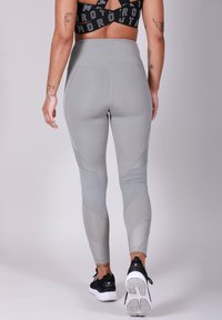 Leggings gris taille haute avec des panneaux en maille et des accents texturés. Fabriqués en matériau lisse et extensible, conçus pour le confort et le mouvement.