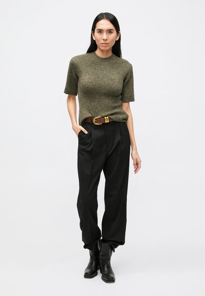 Olivovo zelený krátky sveter s krátkym rukávom zo svetrového materiálu, čierne vysoké nohavice v páse, hnedý opasok so zlatou sponou, čierne členkové topánky. Jednoduchý, voľný strih.