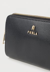 Black leather wallet with a textured finish, gold hardware, and embossed logo. Features a zip closure and clean lines for a sleek design.