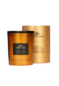 Barattolo per candele in vetro ambra con coperchio nero, etichettato "Passione Segreta" in caratteri dorati. Accompagnato da un imballaggio cilindrico texturizzato dorato.