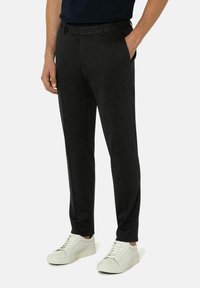 Antrazitgraue Hose mit taillierter Passform, gefertigt aus einem weichen Stoff. Verfügt über Seitentaschen und einen Taillenbund, kombiniert mit weißen Sneakers.