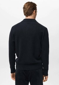 Suéter de punto azul marino con dobladillo y puños acanalados, que presenta un cuello de chal y una textura suave, mostrado desde la parte posterior en un modelo.
