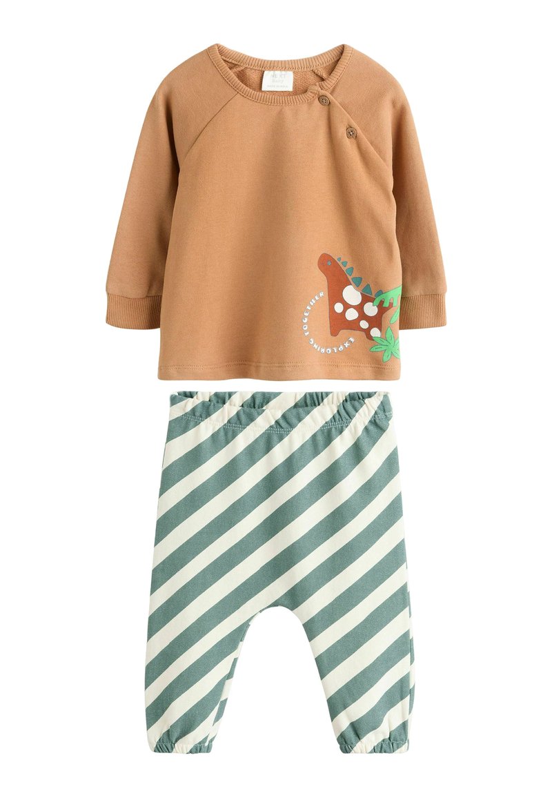 Ruskea puuvillapaita, jossa on dinosauruksen grafiikka ja vihreät yksityiskohdat, yhdistettynä vihreisiin ja valkoisiin raidallisiin elastisiin vyötäröhousuihin.