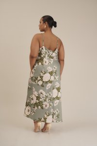 Robe midi florale en tissu vert, dotée d'un corsage ajusté, de fines bretelles et d'une jupe fluide ornée de grandes fleurs blanches et roses.