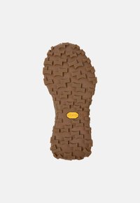 Braune Vibram-Sohle mit einer strukturierten, gemusterten Oberfläche und tiefen Stollen für den Halt. Mit einem gelben Vibram-Logo. Größe 38.