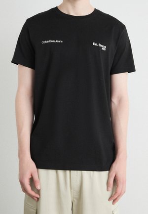 T-shirt en coton noir avec "Calvin Klein Jeans" et "Est. Depuis 1978" brodé en blanc sur la poitrine. Design classique à col rond.