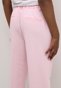 Lichtroze broeken met een elastische tailleband, voorzien van twee achterzakken en een zachte textuur. Slim fit met een rechte pijpdesign.