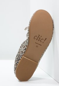 Buty z tkaniny w panterkę, o miękkiej fakturze; brązowa gumowa podeszwa. Na podeszwie znajduje się branding z napisem "clic!" oraz rozmiar "31". Wyprodukowano w Hiszpanii.