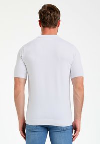 Polo de manga corta en tejido de punto blanco. Presenta un collar clásico y puños acanalados. Textura suave y ajuste ceñido.