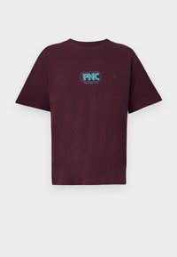 Burgundska bombažna majica s krožnim ovratnikom, kratkimi rokavi in svetlo modrim okroglim logotipom ter besedilom na prsih. Oblikovanje običajnega kroja.
