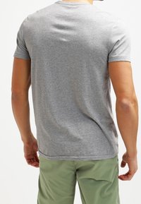 Camiseta de algodón gris con cuello redondo, mangas cortas y una textura suave. Diseño simple, sin patrones ni adornos.