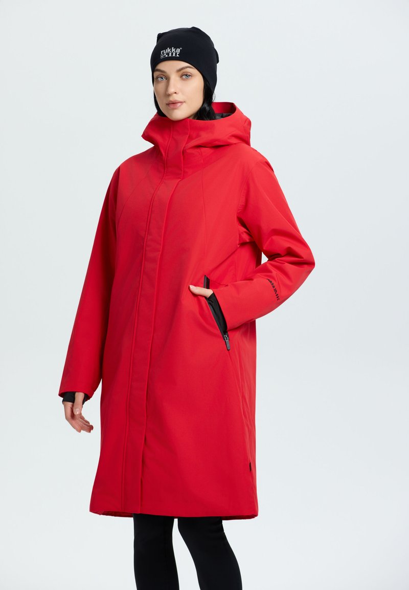 Lungo impermeabile rosso con colletto alto, tasche laterali e dettagli neri. Presenta un cappuccio con cordoncino e una silhouette dritta.