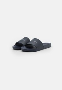 Infradito blu navy con una fascia larga che presenta il logo bianco "Calvin Klein". Realizzate in materiale liscio e resistente, con una soletta morbida.