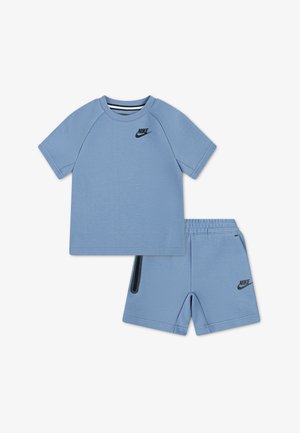 Jasnoniebieski zestaw dziecięcy Nike składający się z koszulki z krótkim rękawem i szortów z elastycznym pasem, z czarnymi logo Swoosh i czarnym akcentem na kieszeni szortów.