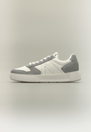 Biały i jasno szary niski sneaker z wiązaniem na sznurówki i grubą podeszwą, pokazany z zewnętrznej strony na neutralnym tle.