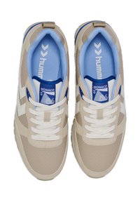 Beige Sportschuhe mit durchbrochener Textur, weißen Akzenten und blauer Innenauskleidung. Verfügt über weiße Schnürsenkel und eine beschriftete Zunge zur Identifikation.