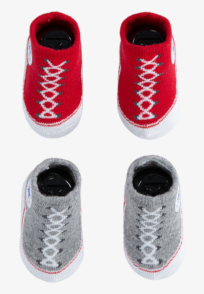Calcetines de bebé tejidos en rojo y gris que parecen zapatillas, con suelas blancas y diseños de cordones. Cuentan con un parche de logo redondo a cada lado.