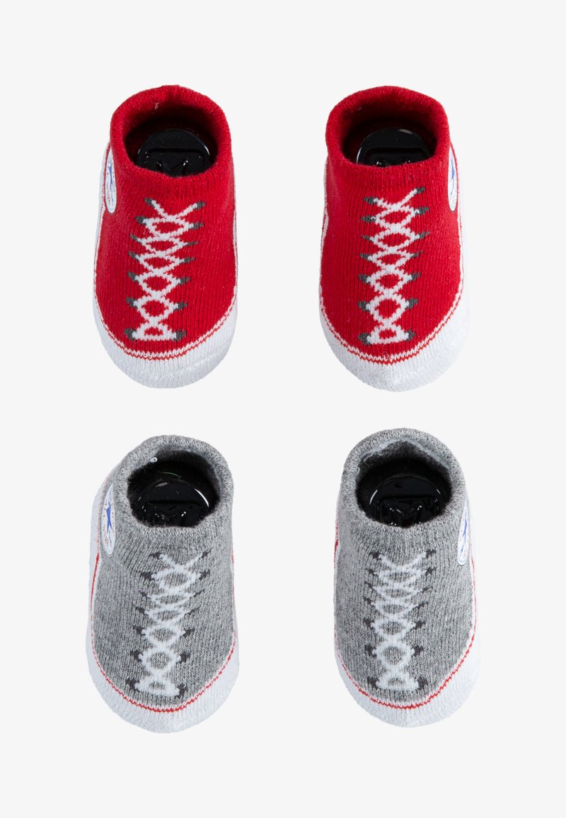 Calcetines de bebé tejidos en rojo y gris que parecen zapatillas, con suelas blancas y diseños de cordones. Cuentan con un parche de logo redondo a cada lado.
