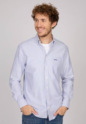 Chemise à rayures bleues et blanches, à manches longues, avec un col, dotée d'une poche poitrine et d'une coupe décontractée. Fabrication en coton.