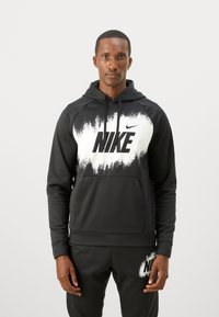 Svart Nike hettegenser med hvit gradientdesign og stort logo. Har en frontlomme og justerbar hette. Materialet ser mykt og glatt ut.