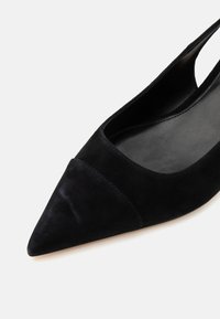 Chaussure femme slingback en daim noir à bout pointu, empeigne basse et semelle intérieure lisse sur fond blanc.