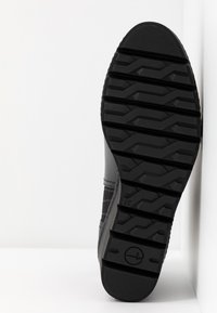 Semelle de botte noire avec un motif de semelle en zigzag profond, taille 37 marquée près du talon, sur fond blanc avec coins.