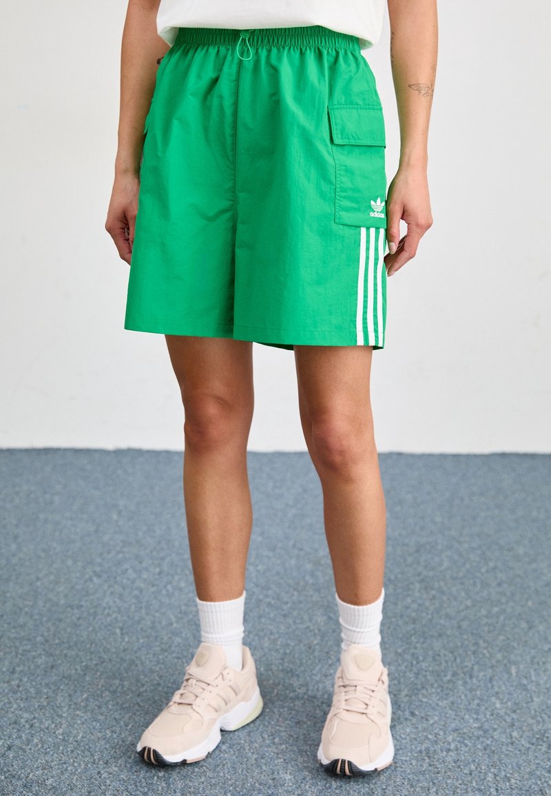 Shorts verts en matériau léger, dotés d'une taille élastique, de poches latérales et de trois bandes verticales blanches sur le côté.