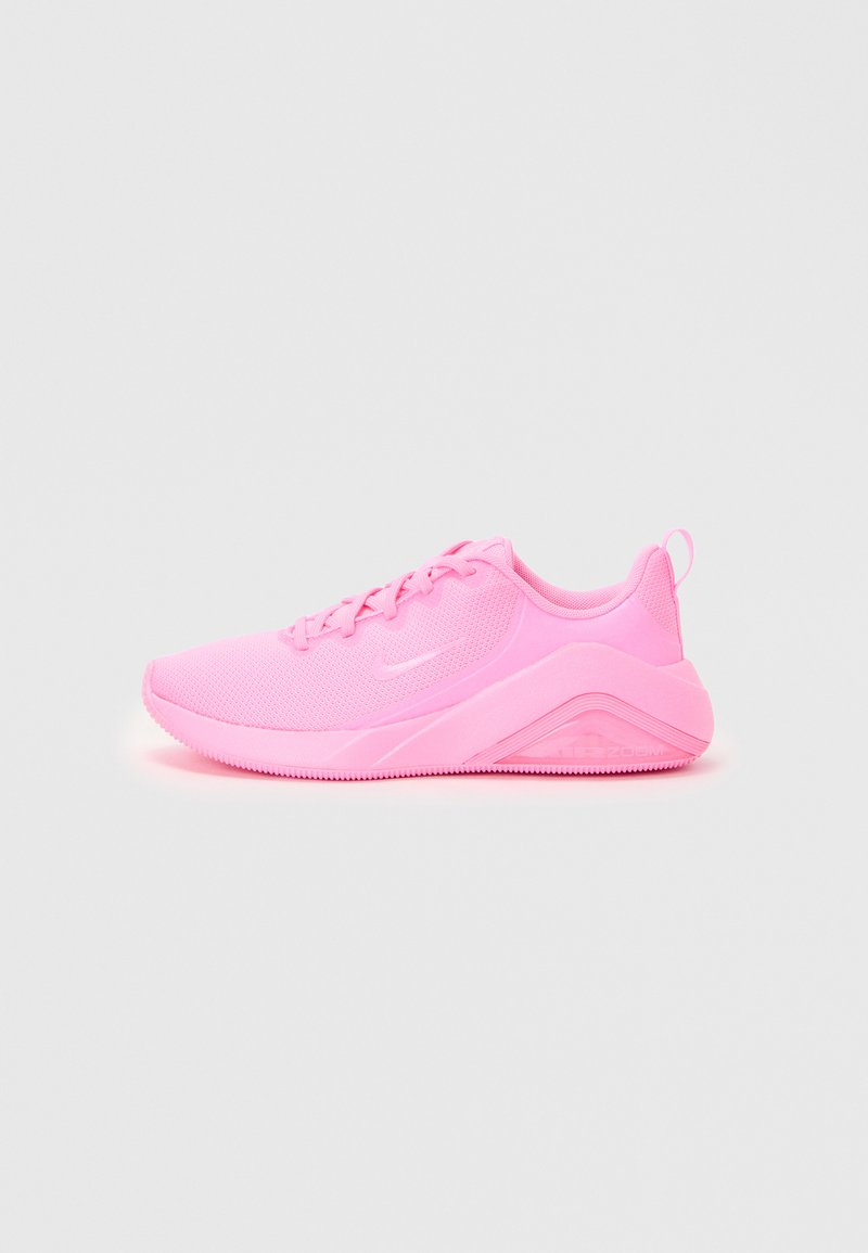 Zapatillas deportivas rosas con una parte superior de malla, puntera redonda y cordones planos. La suela tiene un agarre texturizado y presenta un logo en el lateral.