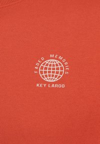 T-shirt in cotone arancione con un grande logo bianco rotondo contenente il testo "Faded Memories" e "Key Largo", centrato sotto un design di un globo.