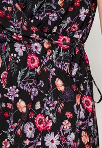 O tecido preto apresenta um padrão floral com flores rosas, roxas e laranjas. Inclui uma cintura com cordão para ajuste e franzidos.
