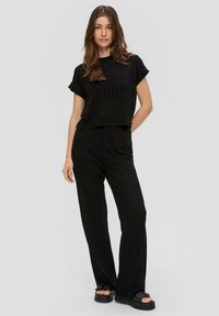 Zwart gestreepte tweedelige outfit bestaande uit een kortmouwtop en wijde broek, gemaakt van lichte stof met een comfortabele pasvorm.