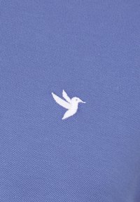 Sinine kootud kangas, millel on vasakul küljel väike valge tikitud kolibri logo. Sile tekstuur koos peene mustriga.