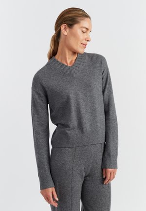 Grijze gebreide trui met een V-hals, geribbelde manchetten en zoom. Zachte textuur en een comfortabele pasvorm; gecombineerd met bijpassende grijze onderkleding.