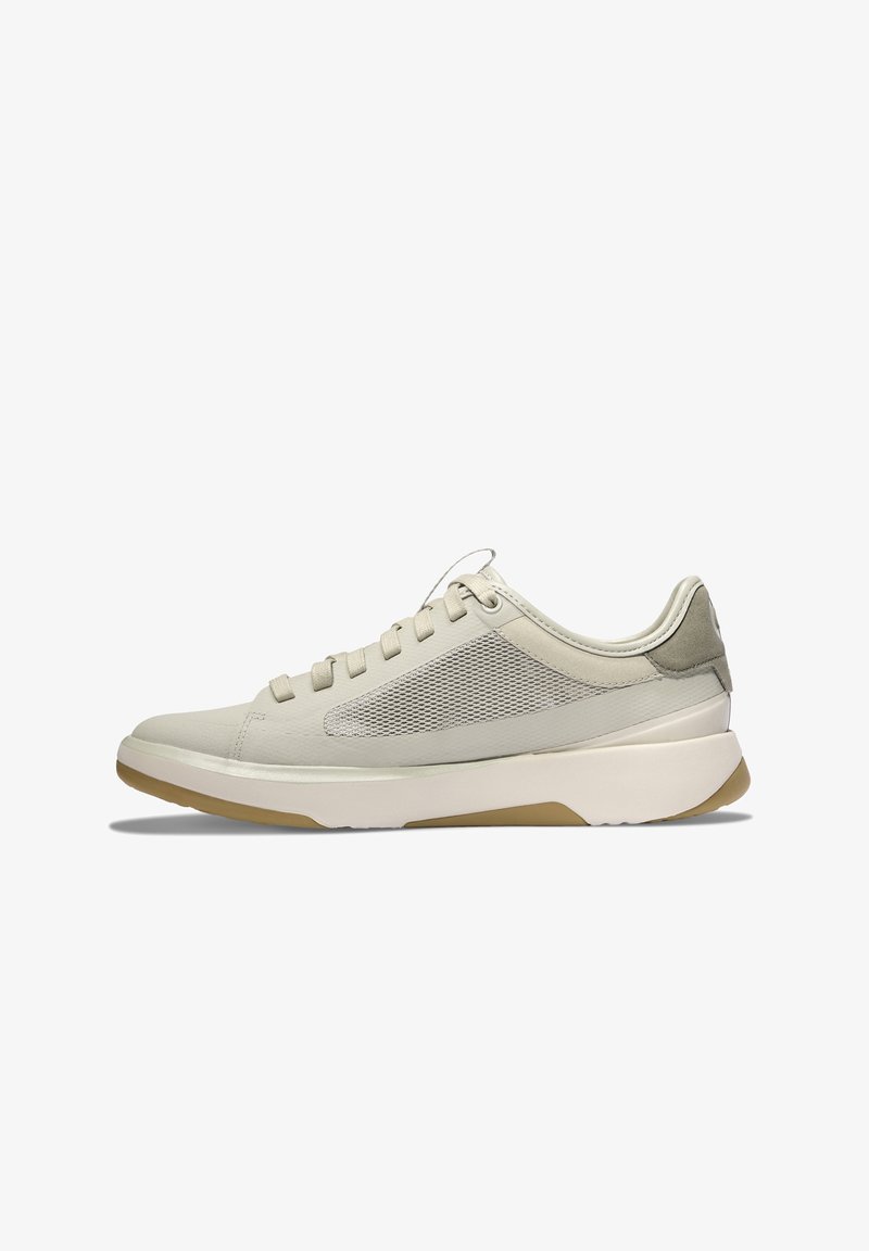 Světlé béžové nízké tenisky s bočními panely z síťoviny, polstrovanou bílou mezipodešví, gumovou podrážkou a šněrováním, z pohledu na střední stranu.