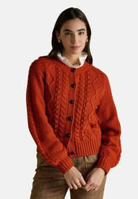 Oranžs adīts kardigāns ar apaļu kaklu, pogu aizdari un ribotu apakšmalu. Iespējas ar teksturētiem rakstiem un garām piedurknēm.