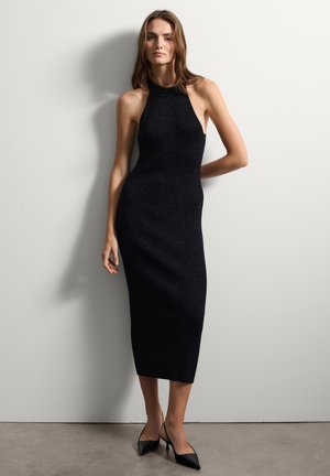 Robe noire sans manches, longueur midi, en tissu texturé avec un col montant, ornée de légers scintillements. Design minimaliste avec une silhouette ajustée.